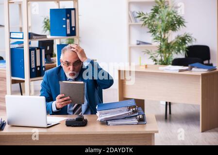 Anziano contabile di sesso maschile infelice con lavoro eccessivo sul posto di lavoro Foto Stock