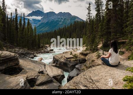 Donna seduta sulle rocce che si rilassa nel Mistaya Canyon nel Jasper National Park, Alberta, Canada. Foto Stock