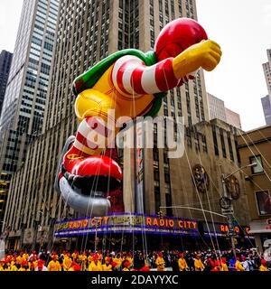 Il pallone Ronald McDonald galleggia in aria durante il Macy's. Parata del giorno del Ringraziamento lungo Avenue of Americas con radio Music Hall sullo sfondo Foto Stock