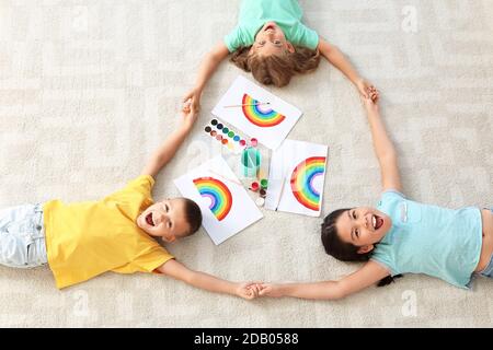 Felici i bambini con dipinti di arcobaleno durante la quarantena Covid-19 a casa, vista dall'alto Foto Stock