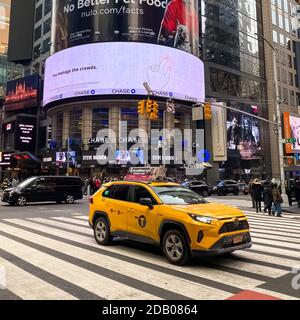 Times Square in inverno a New York City con persone che si spostano e auto e taxi sulla strada. Foto Stock