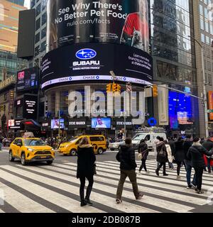 Times Square in inverno a New York City con persone che si spostano e auto e taxi sulla strada. Foto Stock