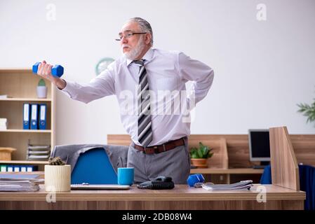 Anziano dipendente che soffre di radicolite sul posto di lavoro Foto Stock