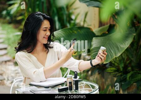 Donna d'affari che fotografa i cosmetici Foto Stock