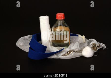 Una vista di una vecchia siringa medica, garza, e flacone isolato su sfondo nero Foto Stock