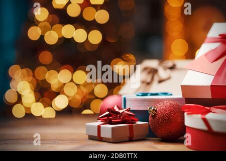 Bei regali di Natale su un tavolo a casa e albero con luci sullo sfondo, festa e concetto di vacanza Foto Stock