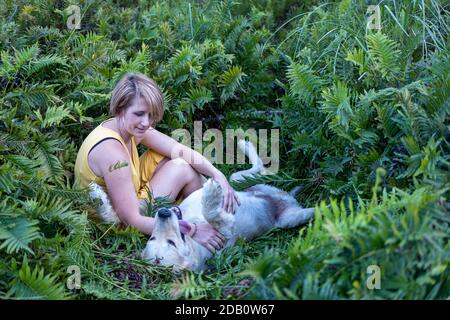 Bionda signora che ama il suo cane Golden Retriever nella foresta Foto Stock