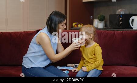 Madre che dà alla figlia un dispositivo di respirazione per respirare. Donna e bambina su coronavirus, covid-19 blocco quarantena pandemia Foto Stock