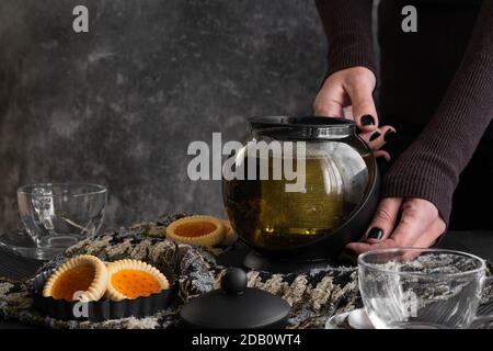 Le mani della donna versano il tè da una teiera Foto Stock