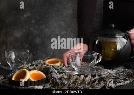 Le mani della donna versano il tè da una teiera Foto Stock