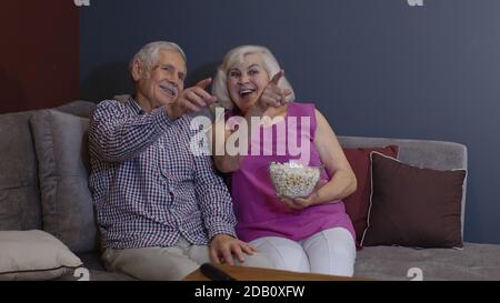 Sorpassato vecchio maturo coppia tifosi di calcio guardando sport tv gioco di sostegno tifoso squadra di calcio vincente sedersi sul divano insieme, felice eccitato senior famiglia celebrare vittoria goal punteggio vista partita televisiva Foto Stock