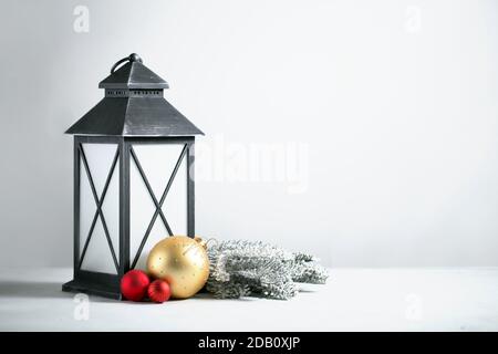 Vecchia lanterna grigia con rami innevati di pino e oro e. Ornamenti rossi sullo sfondo bianco umore di Natale Foto Stock