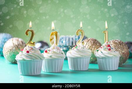 Candele dorate a forma di numeri 2021 su cupcakes. Felice anno nuovo, buon Natale e concetto di auguri di stagione invernale. Spazio di copia Foto Stock