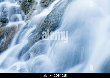 Acqua fresca a fuoco chiuso della cascata tropicale che versa sul calcare durante la stagione della pioggia, acqua pura che scorre su strati di pareti di calcare. Esposizione lunga. Foto Stock