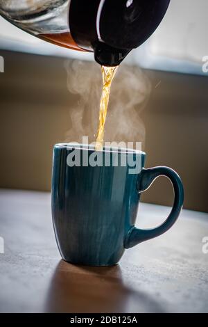 Un uomo che versa il tè in una tazza da una teiera Foto Stock