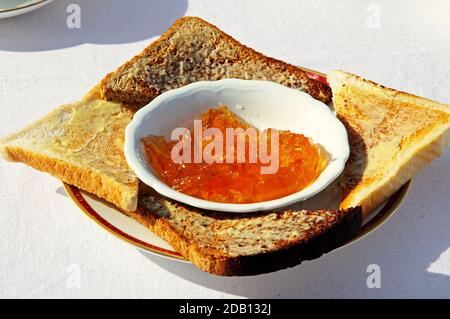 Toast al burro con una ciotola di marmellata d'arancia al centro. Foto Stock