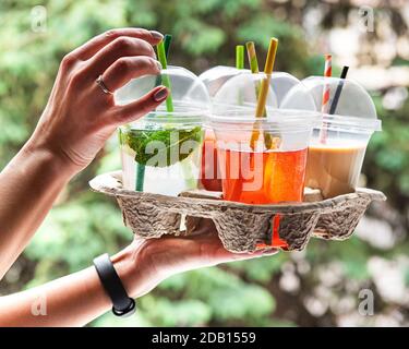 Varie bevande fredde estive e cocktail in un portaditumenti in mano alle donne Foto Stock