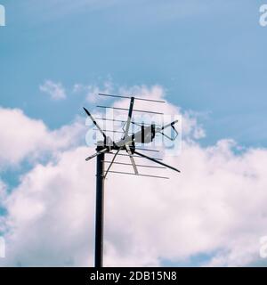 Antenna TV sul tetto contro il cielo blu e le nuvole Foto Stock