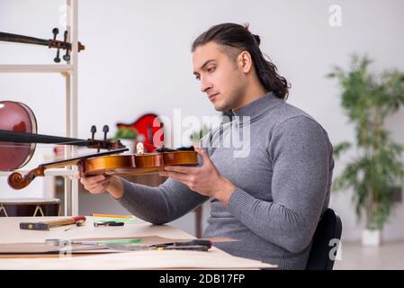 Giovane uomo riparatore che ripara il violino in officina Foto Stock