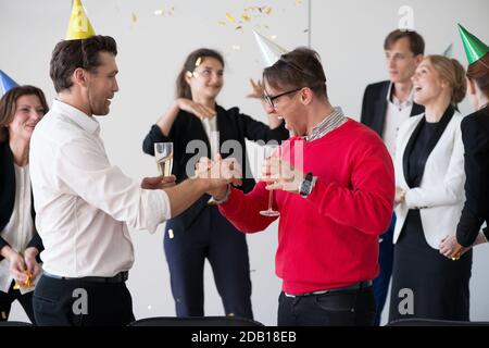Gli uomini d'affari bevono champagne per festeggiare il Capodanno durante la festa in ufficio Foto Stock