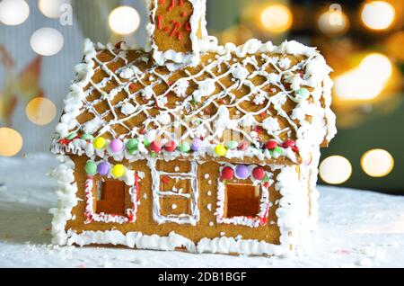 Casa pan di zenzero con luci interne, sfondo scuro boke. Piatto tradizionale e decorazione per la festa di Capodanno e natale. Foto Stock