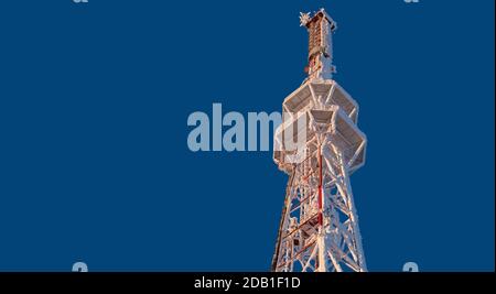 Antenna per telecomunicazioni ghiacciata contro il cielo blu Foto Stock