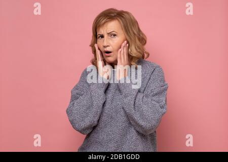 WOW. Donna anziana che guarda eccitato tenendo la sua bocca aperta, mani sulla testa Foto Stock