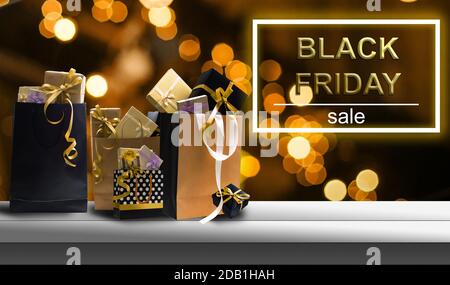 Super sale Black Friday. Scaffale e podio con realistiche scatole da regalo nere con archi in oro. Scritta dorata su sfondo scuro con luce brillante Foto Stock