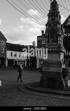 Zafferano Walden UK piazza praticamente deserta, con ornato fontana da bere con turista che guarda verso il basso alla sua macchina fotografica. In bianco e nero Foto Stock