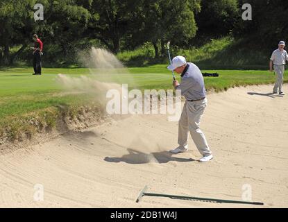 Golfer sfidato comprare un rischio di campo cerca di scheggiare la sua palla sul verde. Foto Stock