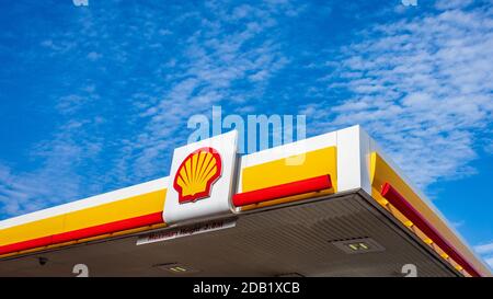 Stazione di benzina Shell, cartello Shell e tetto contro un cielo blu nuvoloso. Stazione di servizio Shell. Stazione di riempimento del serbatoio. Foto Stock