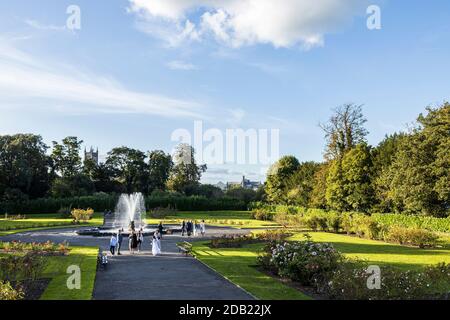 Ragazza in abito di comunione e famiglia presso la fontana e giardini nei terreni del Castello di Kilkenny, County Kilkenny, Irlanda Foto Stock