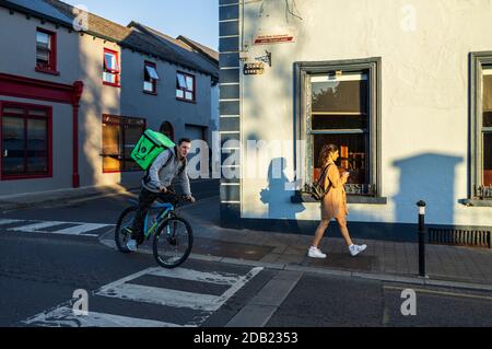 Consegna di cibo ciclista e passersby su John Street fuori Brogans casa pubblica a Kilkenny, County Kilkenny, Irlanda Foto Stock