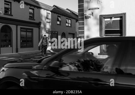 Consegna di cibo ciclista e passersby su John Street fuori Brogans casa pubblica a Kilkenny, County Kilkenny, Irlanda Foto Stock