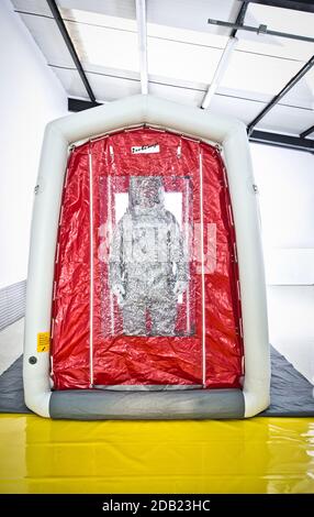 Uomo che indossa una tuta di decontaminazione in piedi nella tenda di decontaminazione. Foto Stock