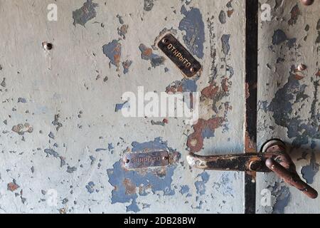 Grungo frammento di porta in acciaio con serratura manuale e marcature in russo Apri, Chiudi Foto Stock