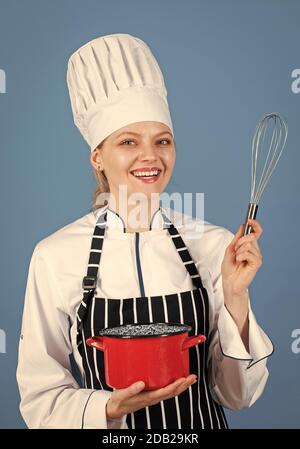 inizio giornata. venite alla mia lezione di cucina. corsi di scuola culinaria. pentole e stoviglie. Cuoca cuoco e masterclass di cibo. Cuoco felice con la casseruola. Donna in grembiule e cappello usa la frusta. Foto Stock