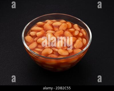 Fagioli cotti in salsa di pomodoro su fondo nero Foto Stock