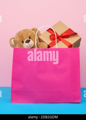sacchetto di carta rosa con un regalo e un orsacchiotto, concetto di shopping e dare un regalo Foto Stock