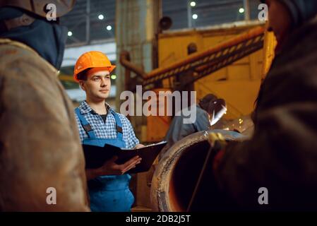 Il maestro e l'equipaggio di saldatori lavora con la costruzione di metallo in fabbrica, abilità di saldatura. Industria metallurgica, produzione industriale di acciaio Foto Stock