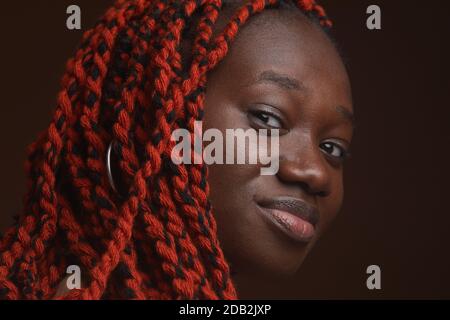 Extreme primo piano ritratto di giovane donna afro-americana con capelli intrecciati guardando la fotocamera mentre si posa in studio Foto Stock