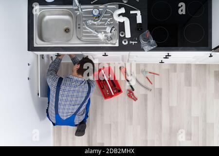 Lavoratore Sdraiato A Pavimento Riparazione Cucina Lavello Con Chiave Regolabile Foto Stock