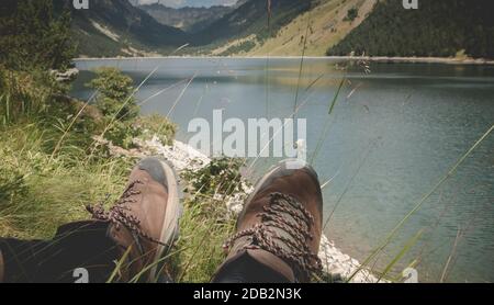 Hiker prendere una pausa seduto vicino al lago di Oule nella valle di Aure in Haute-Bigorre nel dipartimento degli alti Pirenei in Francia Foto Stock