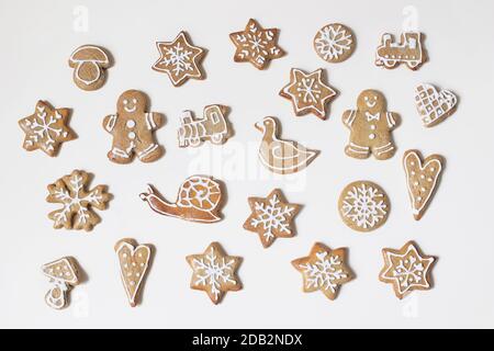 Modello di cibo di Natale. Composizione decorativa invernale di vari biscotti di pan di zenzero con glassa di zucchero isolata su sfondo bianco della tavola. Cuori Foto Stock