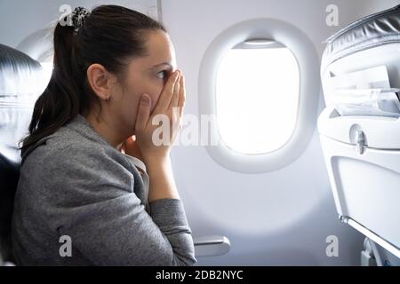 Giovane Donna Che Ha Un Attacco D'Ansia In Aereo Foto Stock