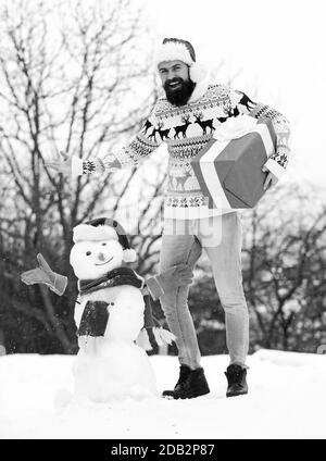 Sogni. Felice hipster pronto per natale. vacanze inverno. un maglione pesante a basse temperature. santa uomo dare presente all'esterno. l'uomo barbuto costruire pupazzo di neve. stagione invernale attività. Auguri di Buon Natale. Foto Stock