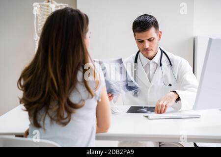 Medico avente la discussione con il paziente circa il ginocchio X-ray Foto Stock