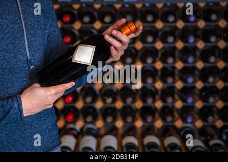 l'uomo presenta una bottiglia di vino raro con chiusura a vite al degustatore nella sala dello spettacolo. Foto Stock