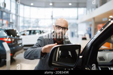 L'uomo controlla la verniciatura del nuovo pick-up nel concessionario di automobili. Cliente nello showroom dei veicoli, uomo che acquista il trasporto, commercio del commerciante dell'automobile Foto Stock