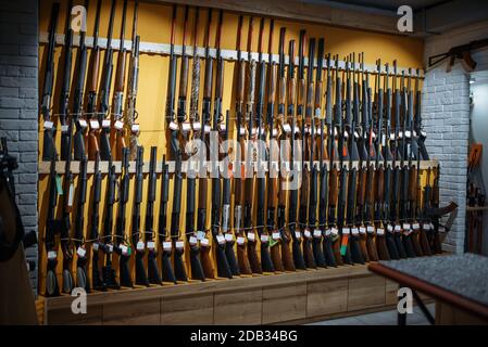 File di fucili sul muro, vetrina in negozio di armi, nessuno. Euqipment per cacciatori in stand in deposito armi, caccia e tiro hobby sport Foto Stock